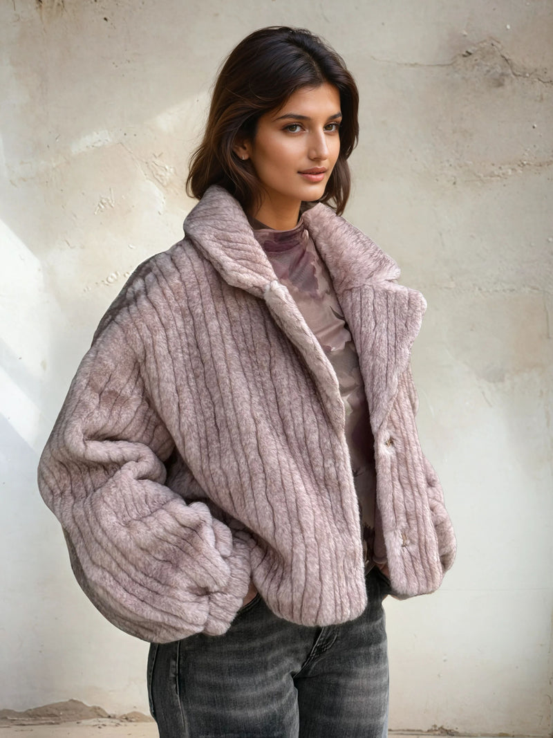 Side angle of a mauve ribbed faux fur short coat with structured collar and plush texture, paired with faded black jeans.