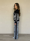 Side view of woman wearing black and white jacquard knit jacket and wide-leg pants with tropical and leopard print design.