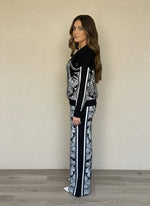 Side view of woman wearing black and white jacquard knit jacket and wide-leg pants with tropical and leopard print design.